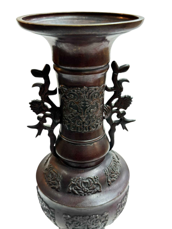 Large Japanese bronze vase with twin handles decorated in relief mythical creature and flower raised on three legs to circular base, 45.5cm.