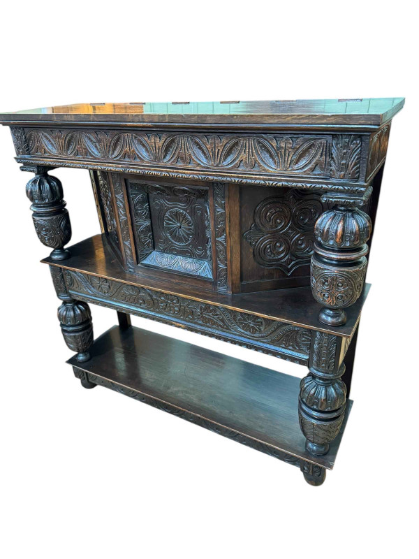 Victorian carved oak buffet, the canopy top above a central door and canted corners with a long drawer and undershelf below, the whole with four carved supports, 119cm by 119cm by 39cm.