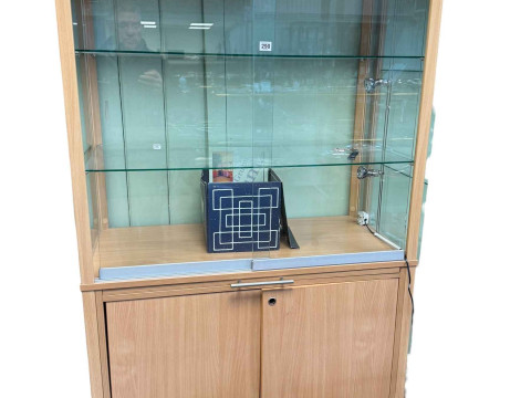 Beech finish illuminated shop display cabinet having two sliding glazed...