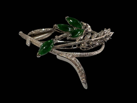 An 18 carat white gold, green jade and diamond set brooch, design as a foliate spray with marquise cut jade and round cut diamonds. thumbnail