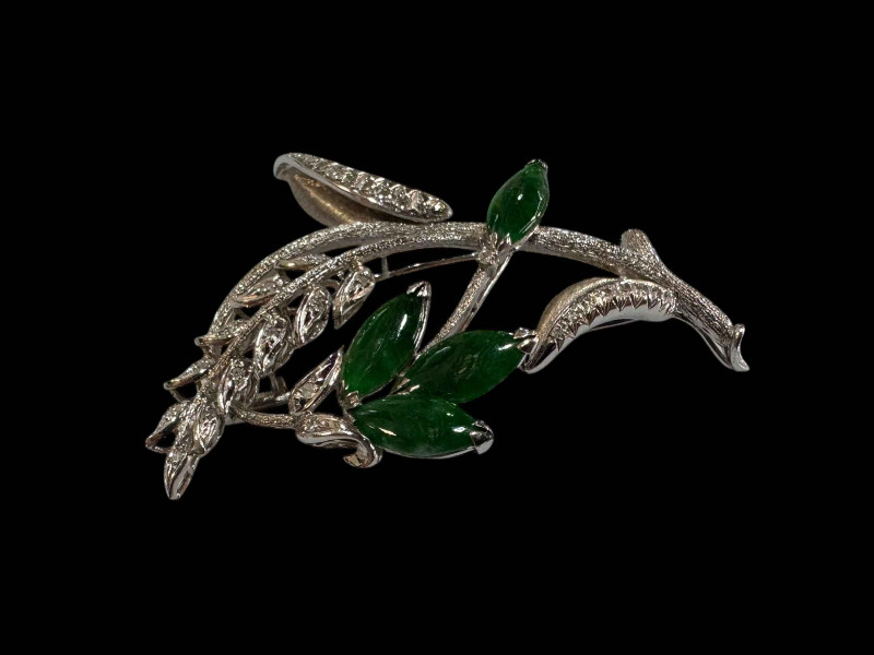 An 18 carat white gold, green jade and diamond set brooch, design as a foliate spray with marquise cut jade and round cut diamonds.