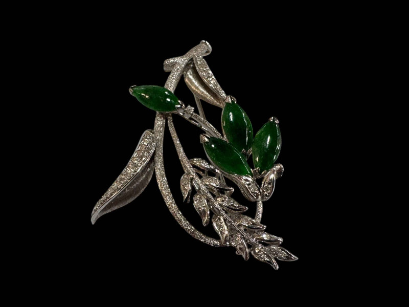 An 18 carat white gold, green jade and diamond set brooch, design as a foliate spray with marquise cut jade and round cut diamonds.
