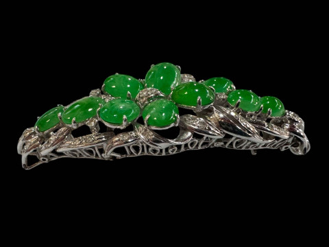 An 18 carat white gold, green jade and diamond set brooch/pendant set with ten cabachon jade stones and round cut diamonds. thumbnail