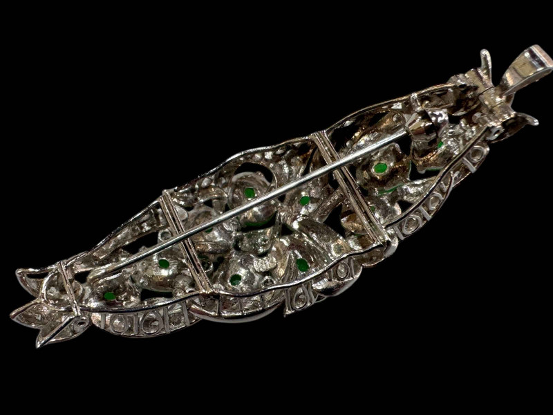 An 18 carat white gold, green jade and diamond set brooch/pendant set with ten cabachon jade stones and round cut diamonds.