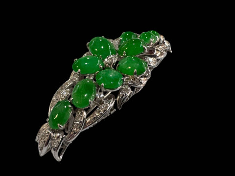 An 18 carat white gold, green jade and diamond set brooch/pendant set with ten cabachon jade stones and round cut diamonds. thumbnail