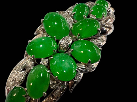 An 18 carat white gold, green jade and diamond set brooch/pendant set with ten cabachon jade stones and round cut diamonds. thumbnail