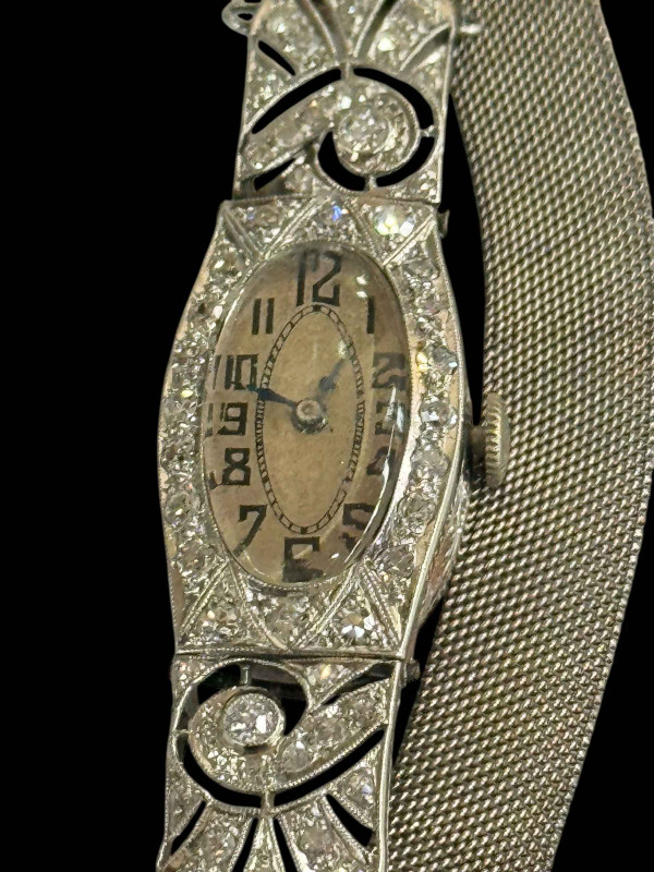 Platinum and diamond set ladies cocktail watch with mesh design bracelet strap, the oval face surrounded by twenty round cut diamonds to hinged diamond set shoulders.