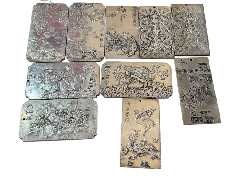 Ten Chinese white metal plaques with embossed designs.