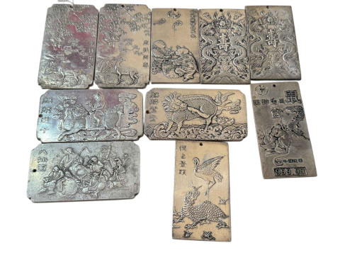 Ten Chinese white metal plaques with embossed designs.