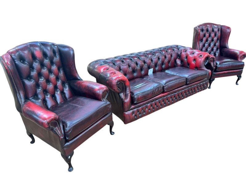 Ox blood buttoned leather and studded three piece Chesterfield lounge suite comprising three seater settee and pair wing armchairs.