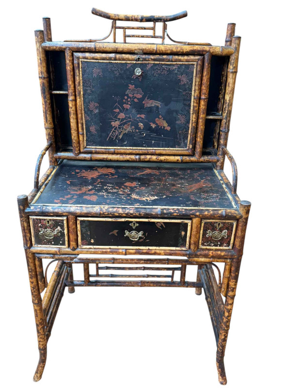 Victorian bamboo and lacquered escritoire, the fall front having leather writing surface and enclosing lacquered stationery compartments, all elevated above three drawer base, with label for Dickins & Jones, Regent St, London, 140cm by 81cm by 52cm.