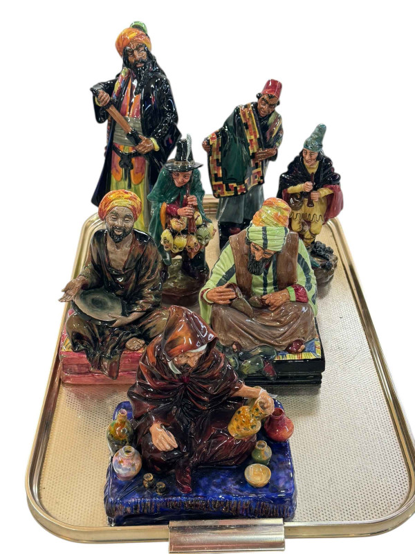 Seven Royal Doulton figures including Blue Beard, Carpet Seller, The Mask Seller and The Potter.