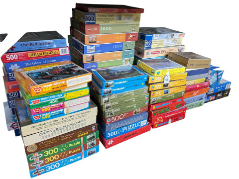 Large collection of jigsaw puzzles including various train illustrations.