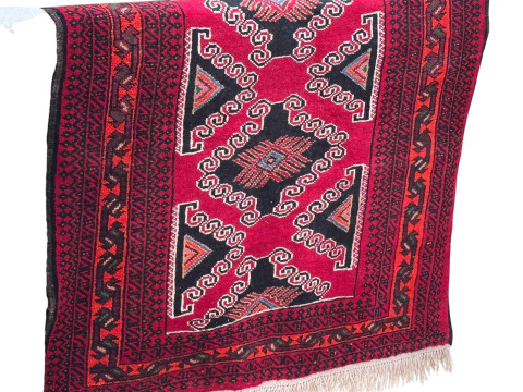 Red ground hand knotted Persian Baloochi rug, 204cm by 125cm.