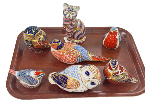 Seven Royal Crown Derby paperweights including cat, owls, and birds.