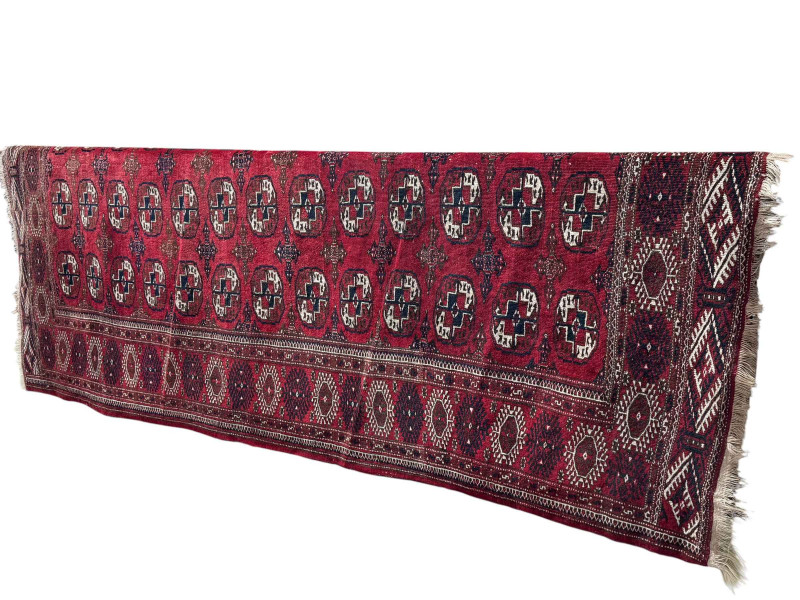 Early 20th Century Tekke Turkoman carpet with repeating boleh pattern and geometric border, 327cm by 112cm.