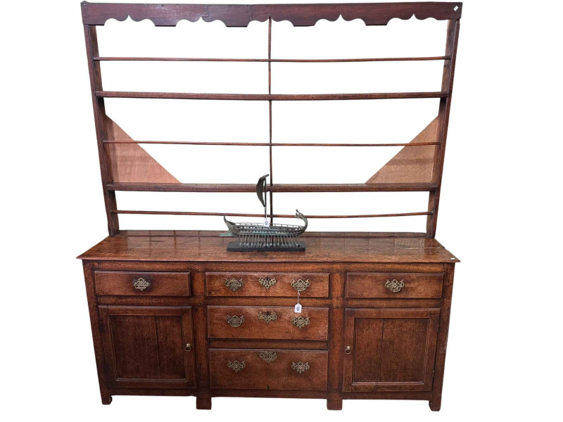 Georgian oak dresser with Delft rack, the base having three graduated central drawers flanked by frieze drawers and cupboards, 183cm by 201cm by 46cm.