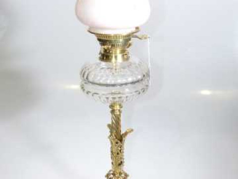 Ornate brass column oil lamp with clear glass reservoir and floral shade