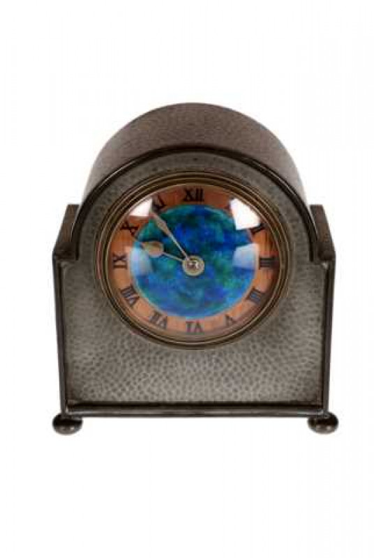 Liberty & Co: A 'Tudric' pewter clock, of shaped hammered form, the copper dial with blue and green enamelled centre, no. 01346. 16cms high.
