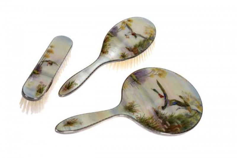 A silver and enamel dressing table set, H. Clifford Davis Ltd, Birmingham 1959, comprising mirror and two brushes, each enamel decorated with ducks in flight.