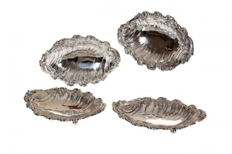 A set of four late Victorian silver dishes, London 1900, each boldly chased with scrolling foliage, raised on four ball feet. Approximately 26.8 troy ozs, 24cm by 16cm