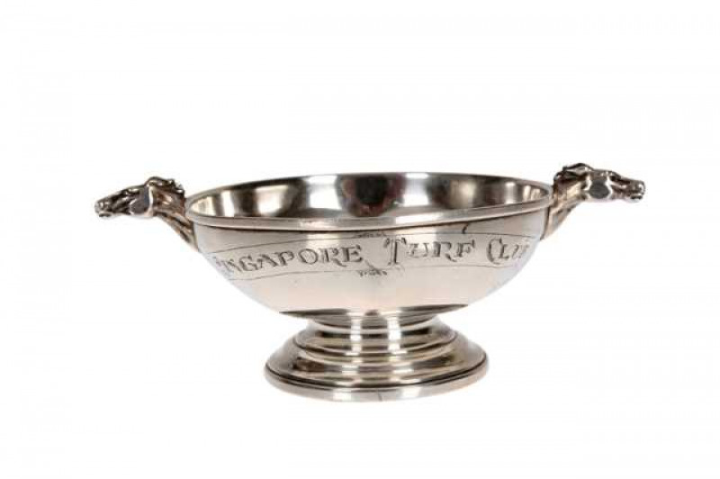 Horse Racing Interest: A small silver bowl, Birmingham 1953, circular faceted form with horses head cast handles, engraved SINGAPORE TURF CLUB, raised on a stepped circular foot. Approximately 3.2 troy ozs, 14cm across the handles