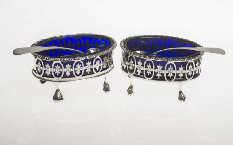 A near pair of Georgian style silver salts, Chester 1923 and Birmingham 1924, oval with blue glass liners, raised on ball and claw feet; together with a pair of Edinburgh silver salt spoons, each engraved with a 'F'. (4)