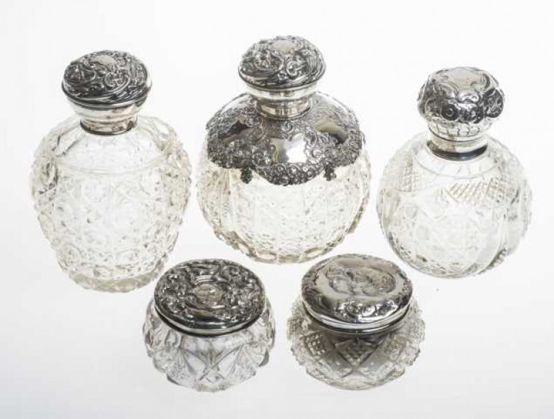 A collection of silver topped and cut glass scent bottles and dressing table jars, comprising three scent bottles and two jars. (5) Largest 12cm