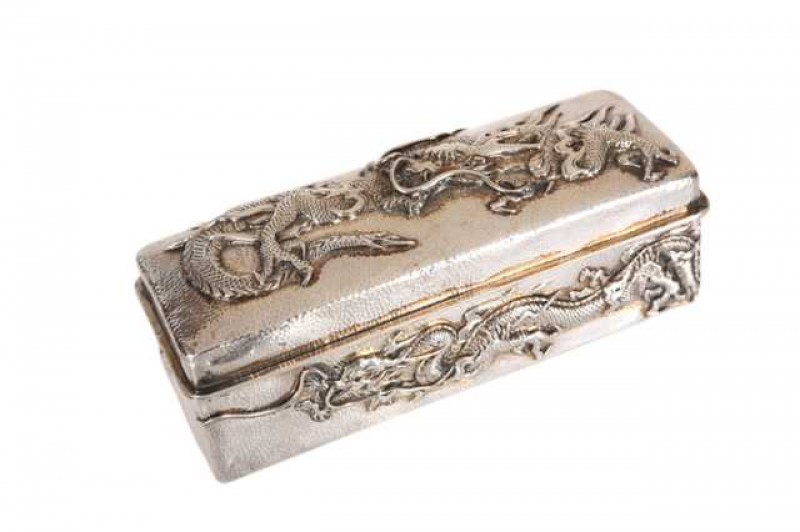 Samurai Shokai, Yokohama: A Japanese sterling silver box, embossed with a dragon to the hinged cover and sides, hammered ground. Approximately 5.9 troy ozs, 5cm by 13cm by 5cm
