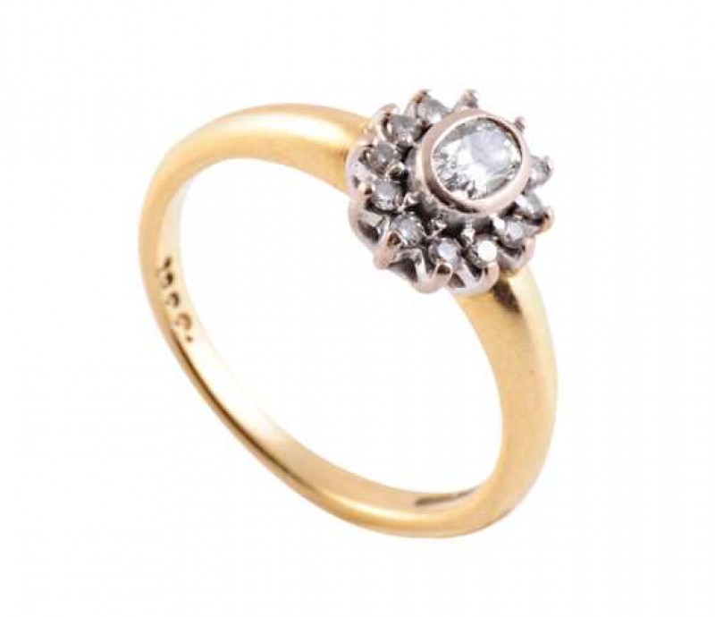 A diamond ring, the central oval cut diamond collet set, raised within a bezel of twelve brilliant cut claw set diamonds, all set in a pierced and open mount between heavy set shoulders on a plain band. Hallmark very worn. Ring size N.