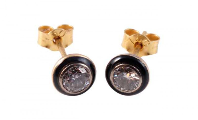 A pair of diamond and enamel stud earrings, the brilliant cut diamond collet set within a simple surround of subtle black enamelling, in a closed mount with post and scroll fittings. Scrolls stamped 750. Weight approx. 1.2gms.