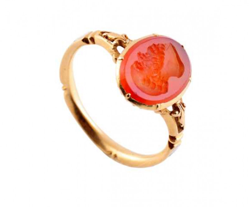 A Victorian carved carnelian and enamel mourning ring, the oval cut carnelian carved with a gentleman's profile, collet set in a closed mount with engraved detailing underneath, between moulded and pierced design shoulders on a moulded band, designed to d
