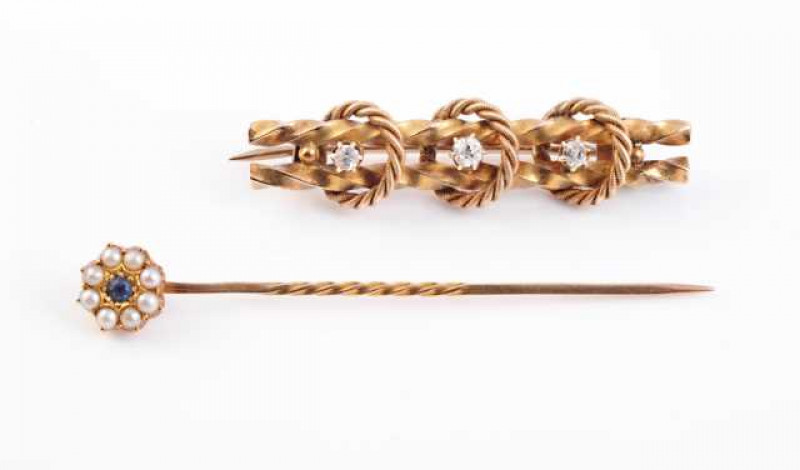 A diamond and yellow gold brooch, the double twisted bars set to the centre with three evenly spaced brilliant cut six claw set diamonds, alternately spaced with three ropework designed loops. Brooch pin fitting. Stamped 15CT. Length approx. 4cm. Weight a