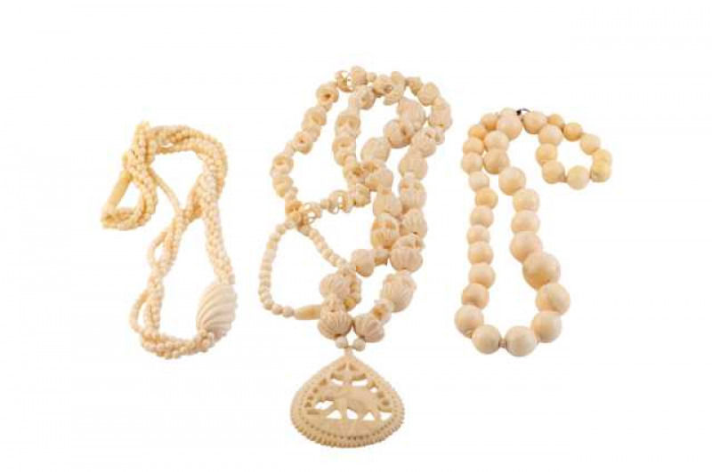 A strand of carved ivory beads, circa 1900, of graduating size, 43cm; together with a four strand ivory bead necklace, of similar date, 42cm; and a carved ivory pendant necklace, carved with elephants, of similar date, 73cm. (3)