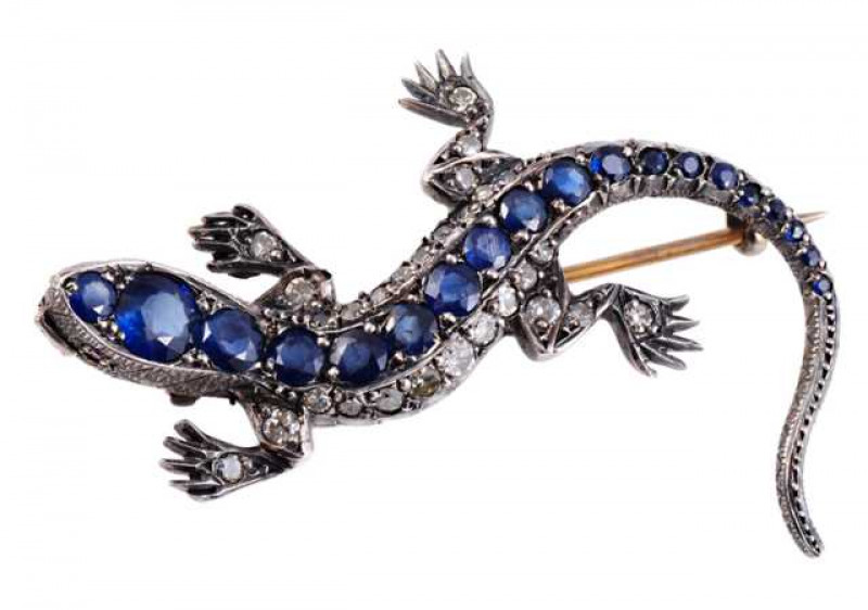 A sapphire and diamond brooch, modelled as a lizard, the realistic design set throughout the body with nineteen graduating round mixed cut sapphires, the limbs and sides set throughout with twenty eight mixed cut diamonds. Brooch pin fitting. Stamped 935.