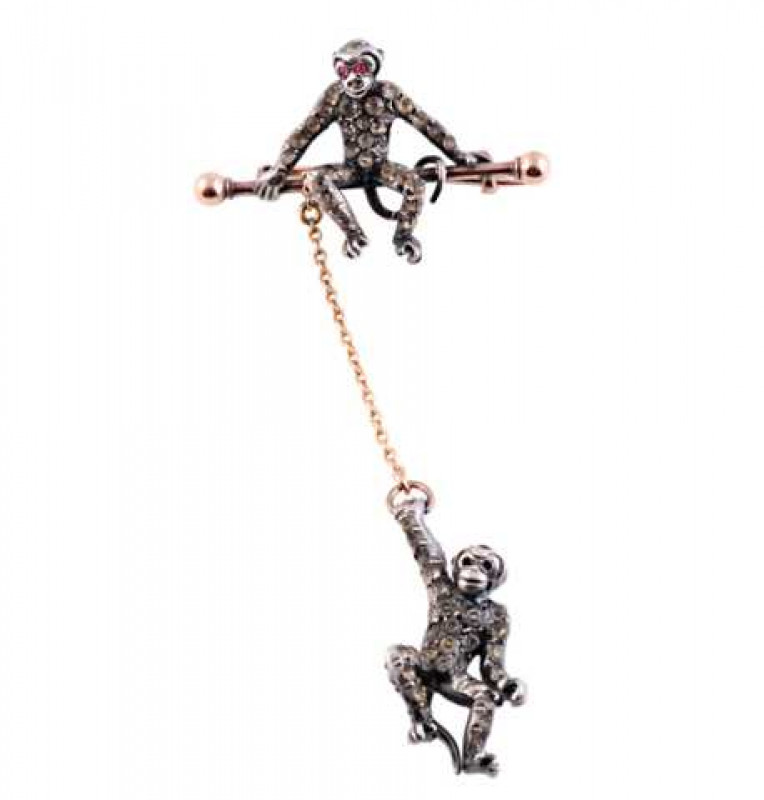 A late Victorian paste set brooch, realistically designed as two monkeys, one monkey swinging on an articulated chain, set throughout with graduating round cut white paste, suspending from a bar brooch on which sits another monkey, similarly set to the fr