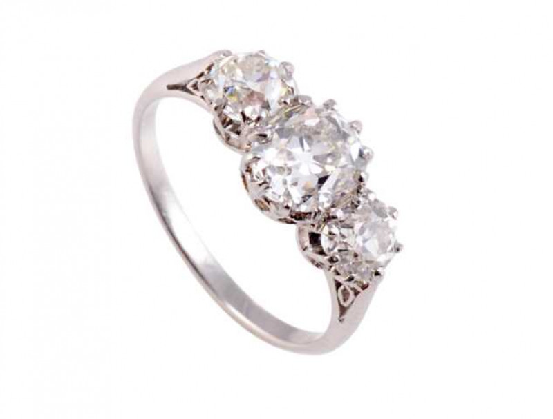 A three stone diamond ring, the large oval mixed cut diamond ten claw set between two smaller brilliant cut nine claw set diamonds, all set in a pierced detail mount between pierced detailed shoulders on a plain band. Ring size L1/2.