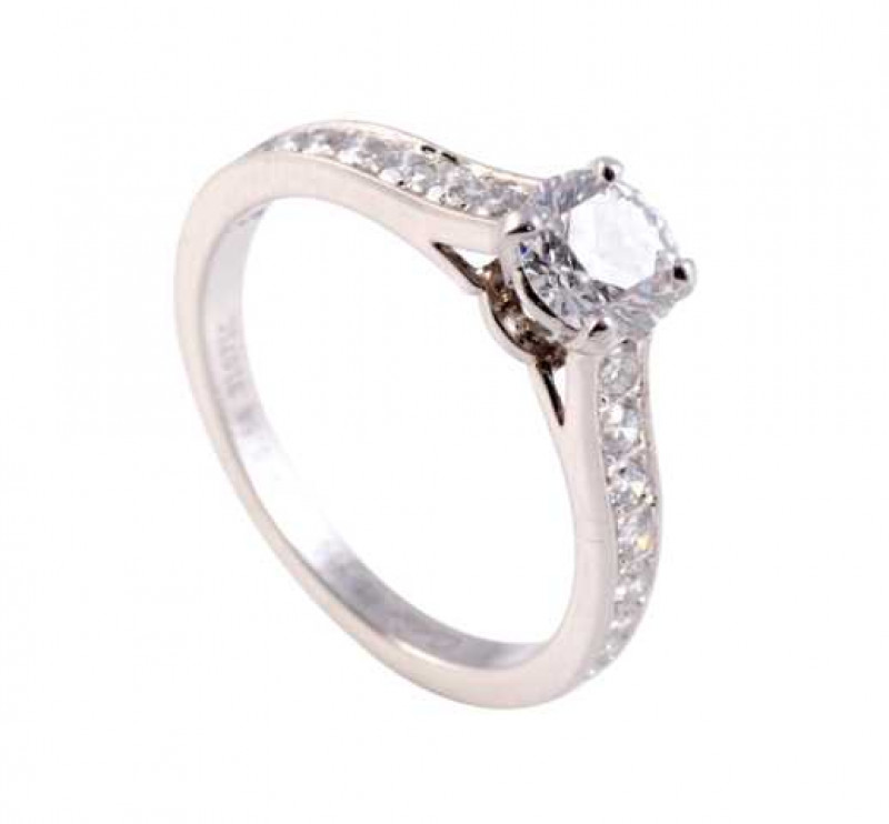 Cartier: A diamond ring, the central brilliant cut diamond four claw set in a raised and open detail mount, set between sloped shoulders set with nine brilliant cut graduating claw set diamonds in open mounts, on a plain band. Stamped PT 950. Makers mark 