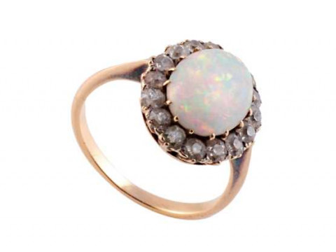 An opal and diamond ring, the oval cut opal claw set within a bezel of...