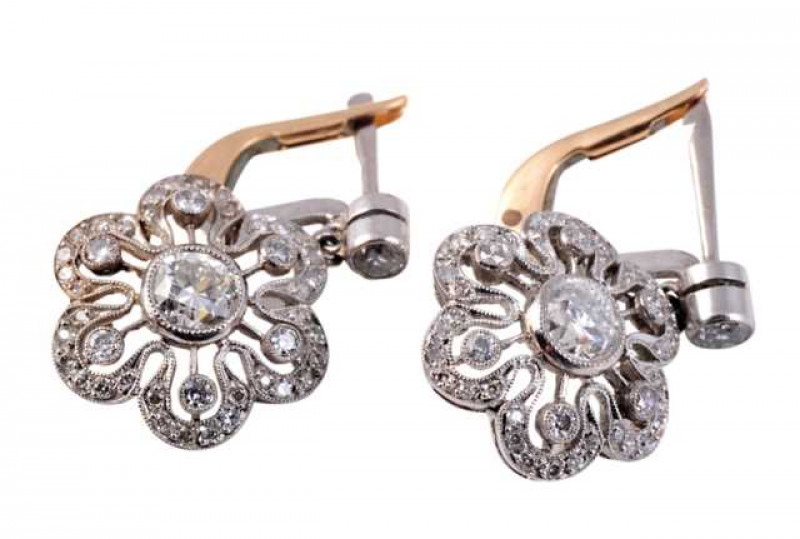 A pair of diamond drop earrings, circa 1900, set to the centre with an old brilliant cut millegrain set diamond, within an intricately pierced flowerhead shaped mount, set to the inner edge with six evenly spaced old brilliant cut millegrain set diamonds,