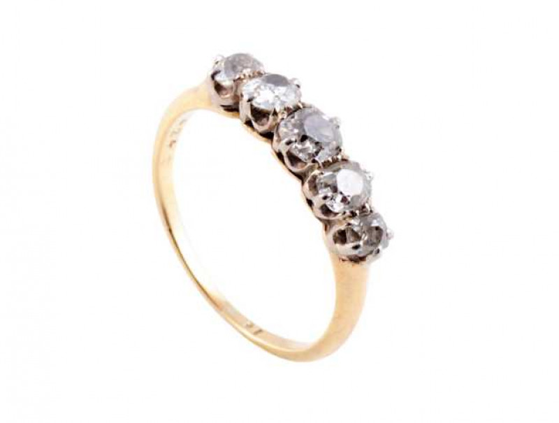 A diamond ring, the five round mixed cut slightly graduating diamonds claw set in a pierced detail mount between slightly tapering shoulders on a plain band. Ring size M.
