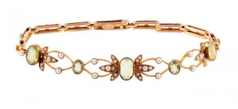 A peridot and pearl bracelet, circa 1900, of symmetrical design, the central oval cut peridot millegrain set between two three-leaf shaped mounts, each set with two or three graduating seed pearl highlights, between two smaller oval cut millegrain set per