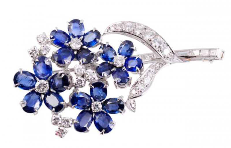 Cartier: A sapphire and diamond brooch, modelled as a spray of flowers, the four flowerheads each set to the centre with a brilliant cut four claw set diamond, all differing in size, set to the centre of five oval cut four claw set sapphires as the petals