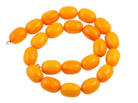 A single strand of twenty two uniform oval shaped amber beads, strung...