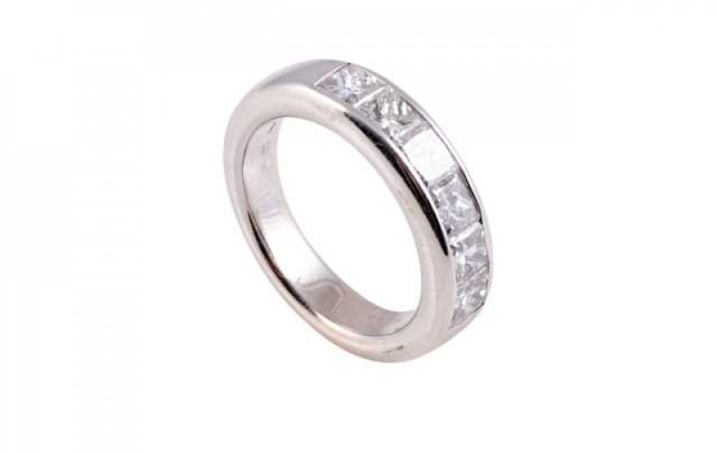 A diamond ring, the six princess cut diamonds channel set to the centre of a heavy mount between plain shoulders on a plain band. Stamped 750. Ring size N1/2