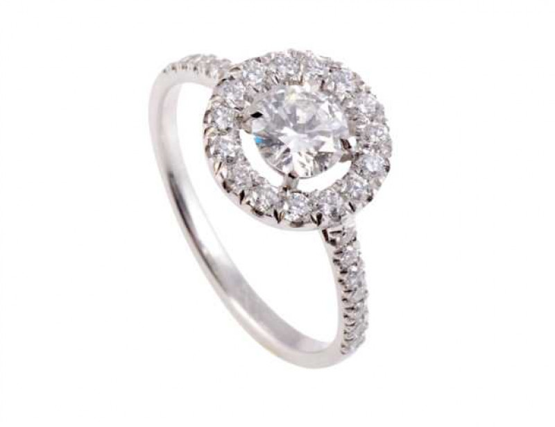 A diamond ring, the central brilliant cut four claw set diamond set within a bezel of fifteen brilliant cut claw set diamonds, all set in an open mount between shoulders each set with seven brilliant cut claw set diamond highlights, on a plain band. Ring 