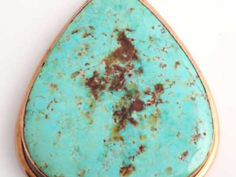 A turquoise pendant, the tapering oval cut turquoise set simply in a collet...