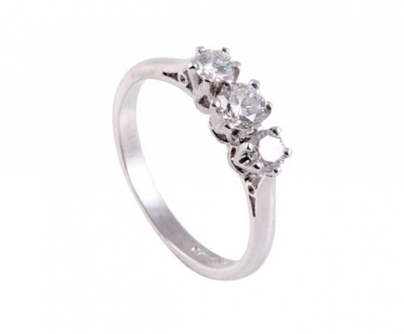 A diamond ring, the three slightly graduating diamonds each five claw set in a pierced detail mount between pierced tapering shoulders on a plain band. Stamped 950. Ring size M.