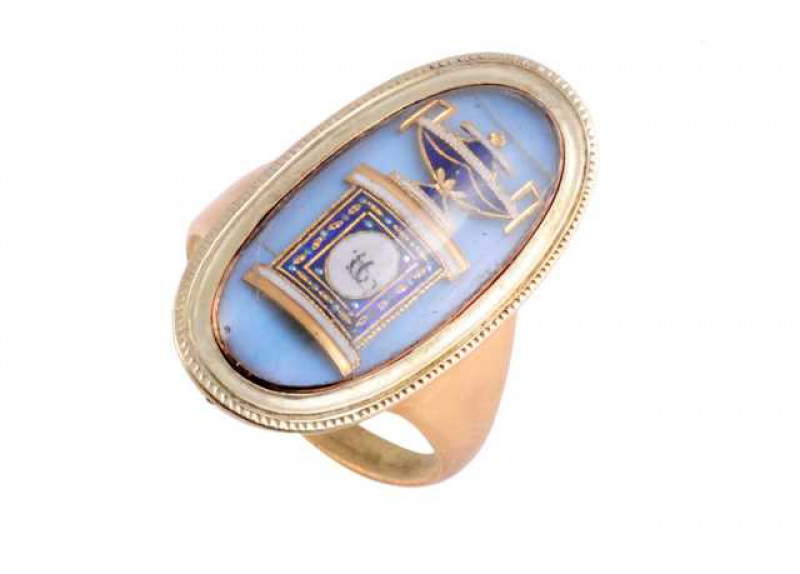 An enamel mourning ring, circa 1790-1800, the oval shaped plaque set with a pale blue enamel ground, the Grecian plinth and bowl design all in dark blue and white enamel with gold detailing under a domed glass covering, the bottom of the mount engraved 'A