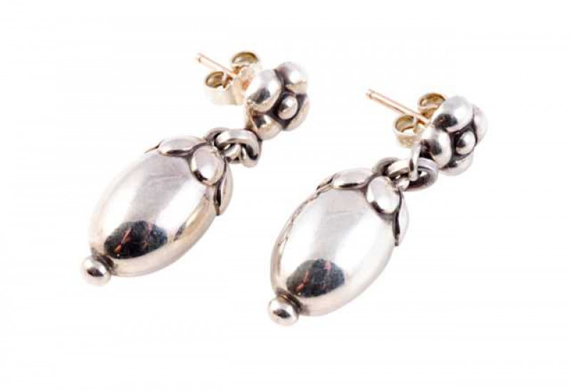 Georg Jensen: A pair of silver earrings, depicting acorns, the large oval drop set to the top with applied petal detailing suspending on an oval articulated link from a moulded flower head shaped link, on post and scroll fittings. Stamped 925 S Denmark. W